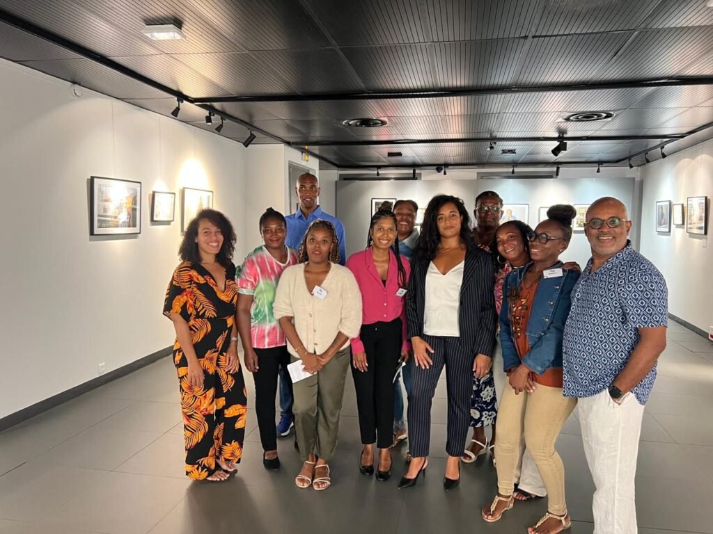 Groupe souriant de bénéficiaires du programme emploi et culture du Musarth, posant devant leurs portraits photographiques lors de la soirée de restitution en Guadeloupe.