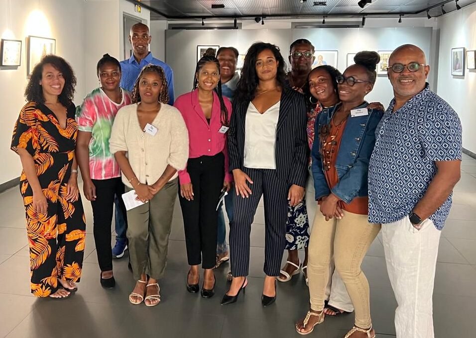 Groupe souriant de bénéficiaires du programme emploi et culture du Musarth, posant devant leurs portraits photographiques lors de la soirée de restitution en Guadeloupe.