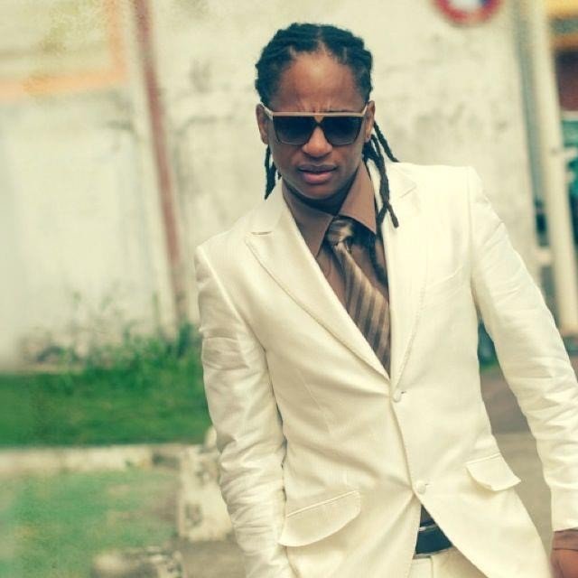 Portrait de Didier Daly en costume clair et lunettes de soleil, photographié en extérieur en Guadeloupe dans le cadre d’un article sur les accusations relayées sur les réseaux sociaux.