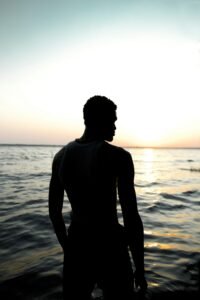 Silhouette face à l’océan au coucher du soleil, illustrant la réflexion sur l’avenir institutionnel de la Guadeloupe