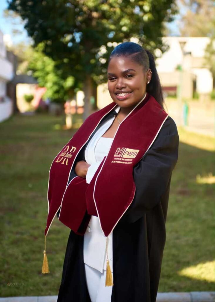 Camille Andrew en toge académique tenant son diplôme de doctorat en médecine obtenu au Maroc